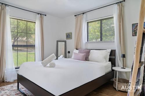 a bedroom with a large white bed with windows at Backyard w Deck, Yoga Space 3BR 2BA Home Parking Near Domain by Austin Vacay in Austin