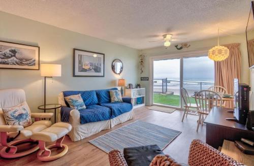 a living room with a blue couch and a table at Oceanfront Suite - Ground Floor in Lincoln City