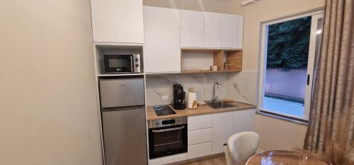 a small kitchen with white cabinets and a window at Juar Villa - Modern Apartments in Tirana