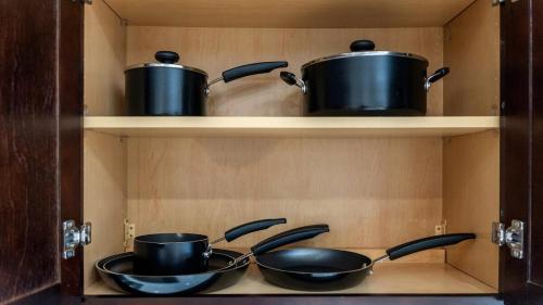 two pots and pans sitting on shelves in a kitchen at Luxury Retreat Walk 2 PATH NYC in Mins Parking in Jersey City