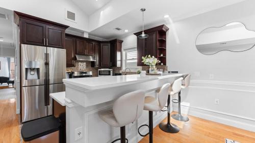 a kitchen with a white island with stools at Luxury Retreat Walk 2 PATH NYC in Mins Parking in Jersey City