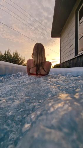 SkierbieszówにあるTwoja Stara Chata z Sauną i Jacuzziの女がスイミングプールに座っている