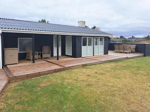 a house with a wooden deck with chairs on it at Cottage Charm Near Lønstrup Lighthouse in Lønstrup