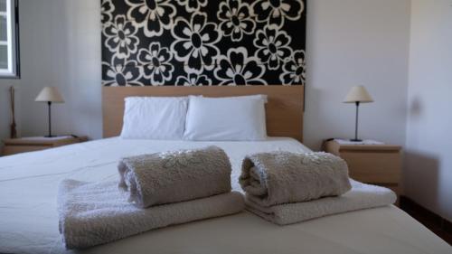 a bedroom with a white bed with towels on it at Monte Sol in São Cristóvão