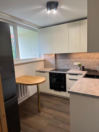 a kitchen with white cabinets and a wooden table at Jelgava Center Apartment with a View and Balcony in Jelgava