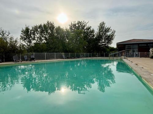 une grande piscine bleue avec le soleil en arrière-plan dans l'établissement Douceur de vivre en Provence, à Saint-Saturnin-lès-Avignon