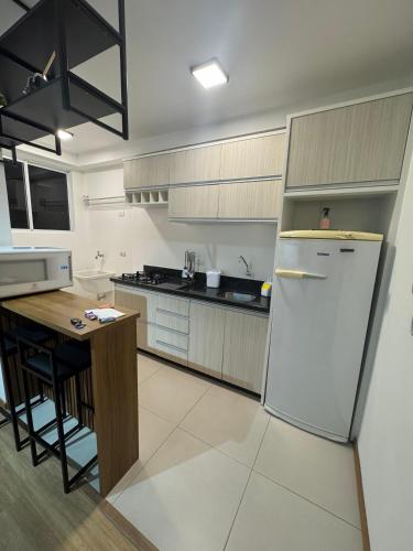 a kitchen with a white refrigerator and a table at Apto novo completo - localização privilegiada in Joinville