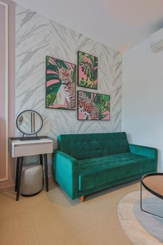 a living room with a green couch and a table at Paxtonz Exsim By NexxField in Petaling Jaya