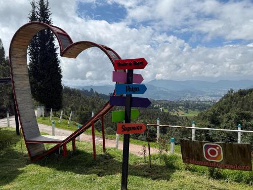 a sign in the shape of an arch next to a playground at El Encanto - La Trinidad, cabaña con jacuzzi in Duitama