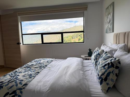 a bedroom with a bed and a large window at El Encanto - La Trinidad, cabaña con jacuzzi in Duitama