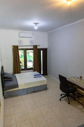 a bedroom with a bed and a desk and a chair at Happy Spiritus Guethouse Tabanan in Tabanan
