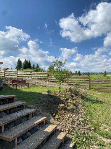 a wooden fence with benches in front of a field at Cabana Ana Toplița in Topliţa