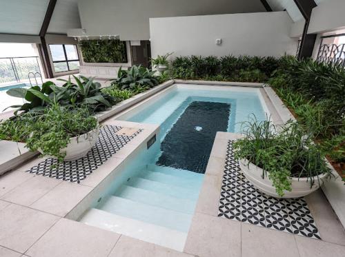 a swimming pool with two potted plants in a building at Paxtonz Exsim By NexxField in Petaling Jaya