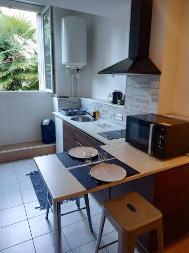 Il comprend une cuisine équipée d'une table avec deux chaises et d'un four micro-ondes. dans l'établissement Agréable studio entièrement équipé, à Périgueux