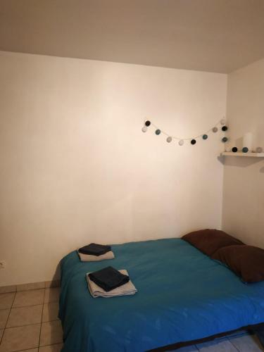 - une chambre dotée d'un lit avec une couverture bleue et un mur dans l'établissement Agréable studio entièrement équipé, à Périgueux
