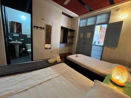 two beds in a room with a mirror and a sink at Sana Mar Hostel & Eco-Café in Santa Marta