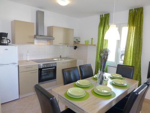 a kitchen with a wooden table with chairs and a dining room at Apartmani Kvesic - Azzurro in Šilo