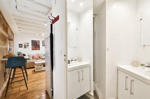La salle de bains est pourvue de 2 lavabos et d'une chaise. dans l'établissement Modern Parisian Retreat Cozy T2 in Paris 02, à Paris
