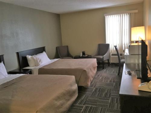 una camera d'albergo con due letti e una televisione di Sunlac Inn Devils Lake a Devils Lake