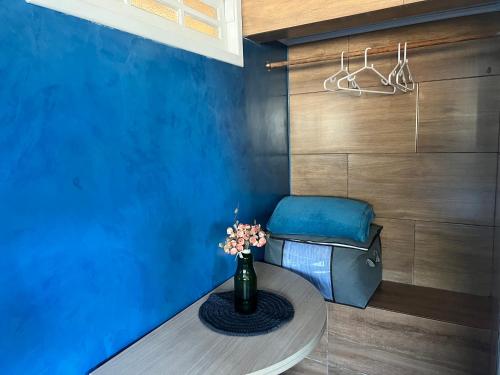 a blue room with a table with a vase of flowers at Suíte Recanto da Serra in Miguel Pereira