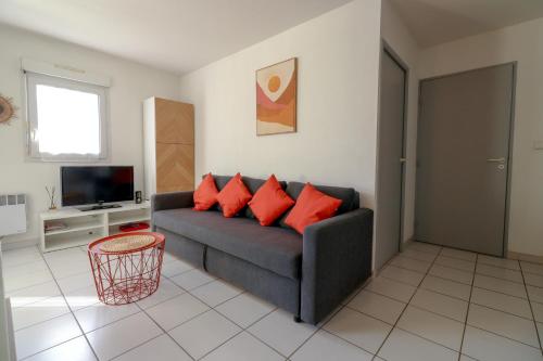 un salon avec un canapé gris avec des coussins rouges dans l'établissement Palmera by Pom, parking, piscine, au Cap d'Agde