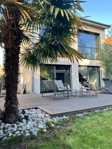 une terrasse avec des chaises et un palmier devant une maison dans l'établissement Maison Paris Stade de France Aeroports, au Blanc-Mesnil