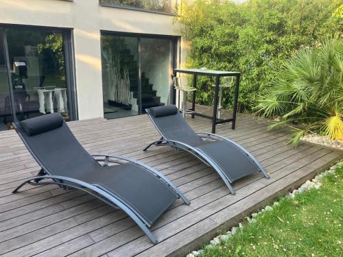 deux chaises et une table sur une terrasse en bois dans l'établissement Maison Paris Stade de France Aeroports, au Blanc-Mesnil