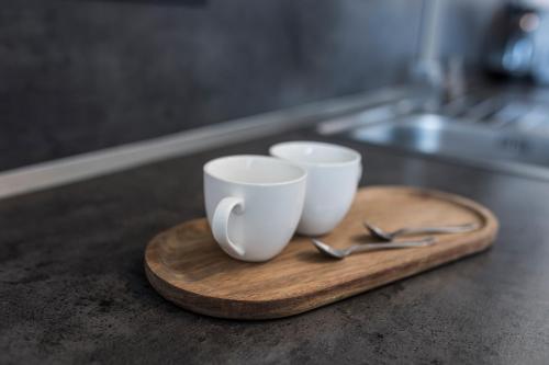 three coffee cups and spoons on a wooden tray at M.F. in Znojmo