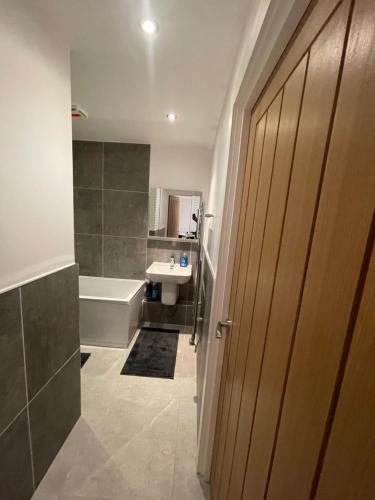 a bathroom with a tub and a sink and a door at Lovely 1 bed apartment in the heart of High Wycombe town centre in High Wycombe