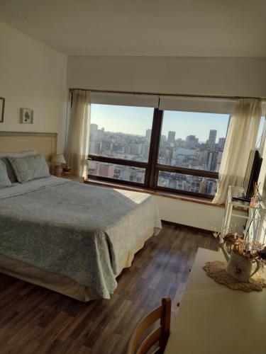 a bedroom with a bed and a large window at Departamento Corrientes Av. in Buenos Aires