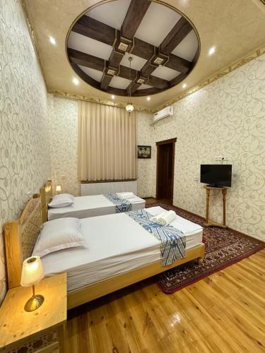 a bedroom with two beds and a flat screen tv at Firdavsiy Guesthouse - Уютный Апарт-отель у озера in Bukhara