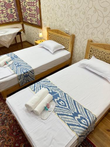 two beds in a hotel room with towels on them at Firdavsiy Guesthouse - Уютный Апарт-отель у озера in Bukhara