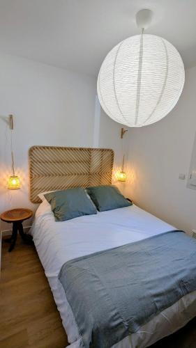 une chambre avec un grand lit et un lustre dans l'établissement La Petite Maison dans la Pinède, à Lacanau