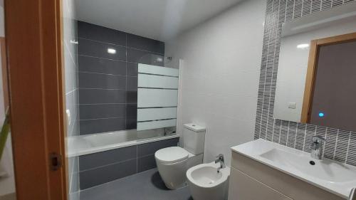 a bathroom with a toilet and a sink and a mirror at Este in La Playa de la Torre de Piles