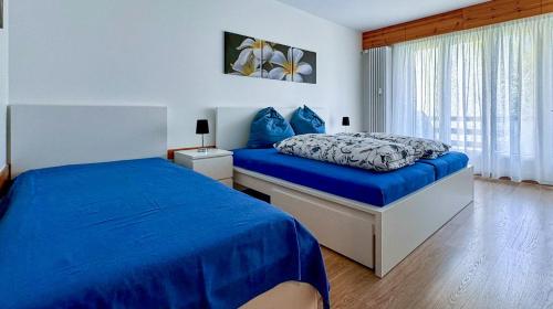 a bedroom with a bed with blue sheets and a window at Zentrale Wohnung in St. Moritz mit großem Balkon in St. Moritz