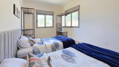 a room with two beds and two windows at Tabarja Hills apartment in ‘Ayn aş Şughayrah