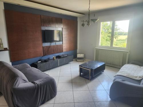 un salon avec un canapé et une télévision à écran plat dans l'établissement Maison avec Jardin et Jacuzzi, à Lesneven