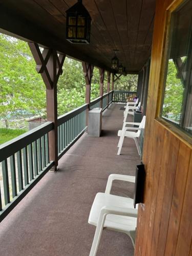 a porch with white chairs on a building at au pied du nord in Saint-Jérôme