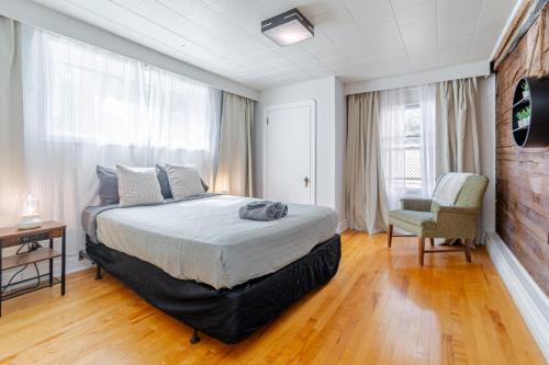 a bedroom with a large bed and a chair at Old-Time Charm - 12 Guests - Billiards & Hot Tub in Sainte-Anne-de-Beaupré