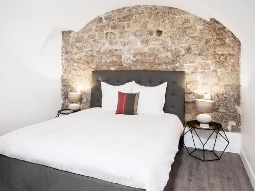 - une chambre avec un grand lit blanc et un mur en pierre dans l'établissement Charming 2BR-2BA between le Marais & le Louvre, à Paris
