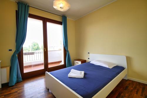 a bedroom with a bed with blue sheets and a window at Villa Mattei in Oristano
