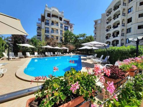 a swimming pool with chairs and umbrellas next to a building at Cozy apartment on Sunny Beach in Sunny Beach