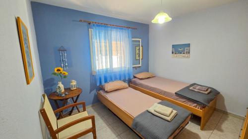 ein kleines Schlafzimmer mit 2 Betten und einem Stuhl in der Unterkunft Potidaia The Garden Oasis Summer House in Nea Potidaea