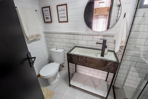 a bathroom with a toilet and a sink and a mirror at Refúgio Romântico - Lareira Externa, Rede suspensa, Netflix e Churrasqueira in Imbituba
