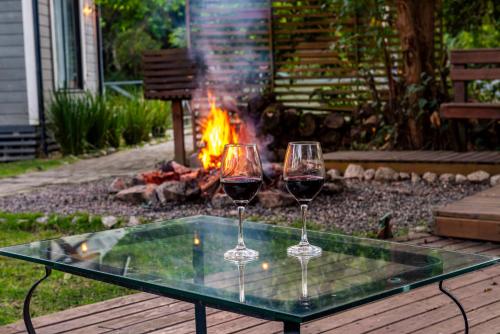 two glasses of wine sitting on a table in front of a fire at Refúgio Romântico - Lareira Externa, Rede suspensa, Netflix e Churrasqueira in Imbituba