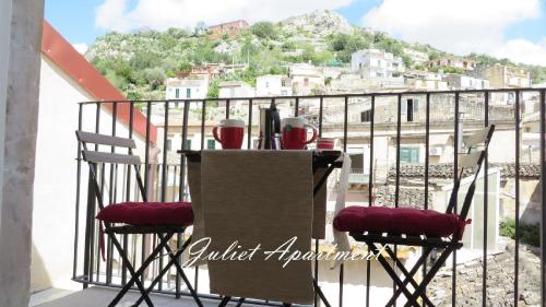 a table with two chairs and red glasses on a balcony at Modica-Apartments in Modica