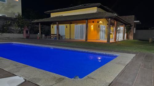 a blue swimming pool in front of a house at night at Jacuipe beach house in Camaçari