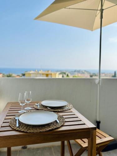 - une table en bois avec 2 assiettes et des verres à vin dans l'établissement Studio moderne et lumineux avec balcon vue mer à Bandol, à Bandol