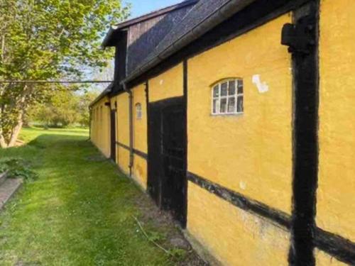 a yellow building with a window on the side of it at Authentic Farm Close To The Water On Samsø in Ballen