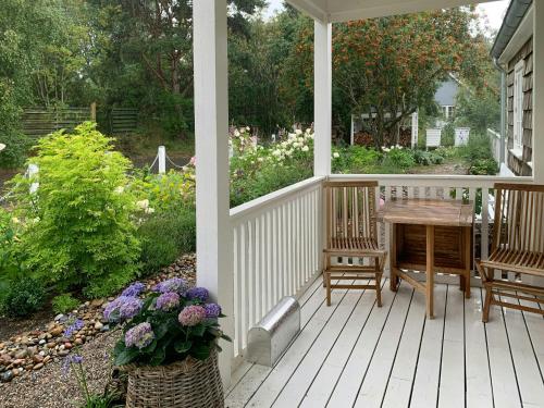 a porch with a table and chairs and flowers at New England Inspired Holiday Home In Rågeleje in Vejby